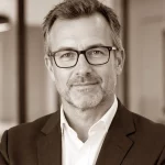 Testimonial Dunkelweiss Coaching in Aachen mit Rupert Freutsmiedl Thomas K: Mann mit Brille und Anzug