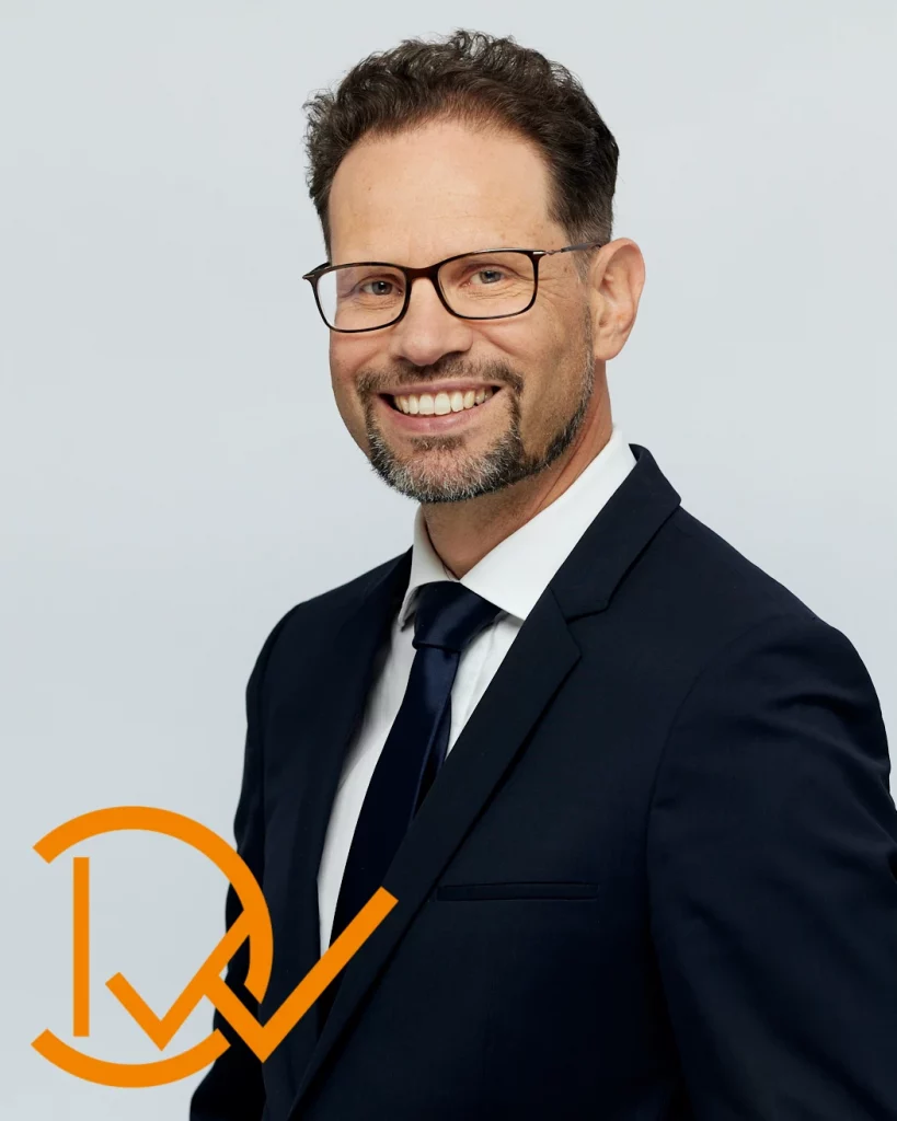 Zufriedenheitsgarantie_dunkelweiss_coaching_Rupert Freutsmiedl_MB_Babor_2310-51879 Sinnbild Zufriedenheitsgarantier für Coaching mit Rupert Freusmiedl von dunkelweiss: Mann in Anzug mit Brille lächelt.
